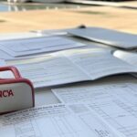 Pilha de documentos burocráticos em escritório governamental de Brasília, representando lei de primeiros socorros em concursos aprovada pela CLDF com críticas por burocracia.