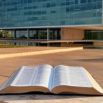 Bíblia aberta como patrimônio cultural em Brasília, com Congresso Nacional ao fundo, ignorando laicidade pela CLDF.