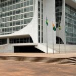 Edifício do Tribunal de Justiça no Brasil com bandeiras a meio mastro em luto pela morte de desembargador.