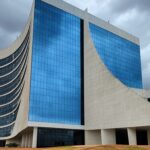 Fachada do TJDFT em Brasília com bandeiras a meio mastro, simbolizando luto pela morte de desembargador.