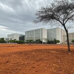 Vista urbana de Brasília com edifícios modernos e pouca arborização, ilustrando atraso em política ambiental.