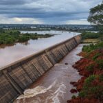 Transbordamento do Reservatório do Descoberto com águas inundando áreas no DF, expondo riscos de inundações.