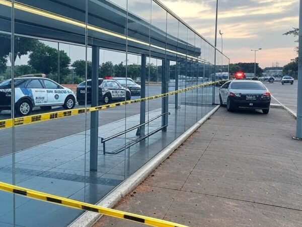 Parada de ônibus em Brasília com fita de isolamento policial e viaturas, representando cena de investigação no DF.