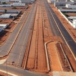 Obras de pavimentação e ciclovias em rua de Ceilândia, com máquinas e demarcações, representando licitação da Terracap.