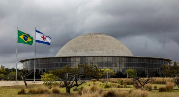 Congresso Nacional em Brasília com documentos acumulados, representando atrasos na regulamentação de lei antissupremacista e falhas no Distrito Federal.