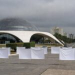 Edifício da CLDF em Brasília com faixas roxas simbolizando superação e falhas no combate à violência contra mulheres.