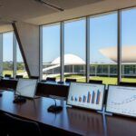 Imagem de laptop com ícones de proteção online em sala brasileira, representando debate sobre lei ECA Digital para jovens.