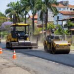 Obras de recapeamento asfáltico na Avenida Del Lago no Itapoã, com máquinas e sinalizações de trânsito.